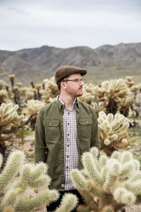 Young man profile in cholla cactus field with hills in the background