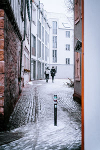 Man walking on snow covered street amidst buildings in city