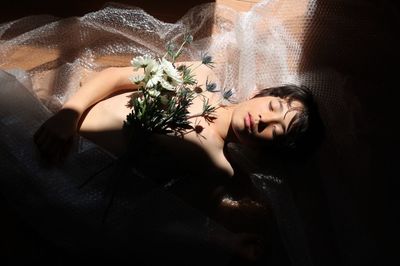 High angle view of dead boy lying with flowers and bubble wrap on floor