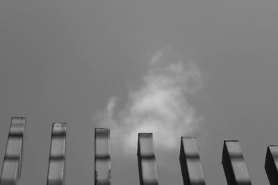 Low angle view of smoke stack against sky in city