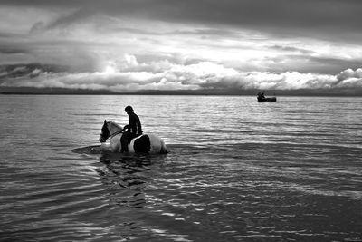 People in sea against sky
