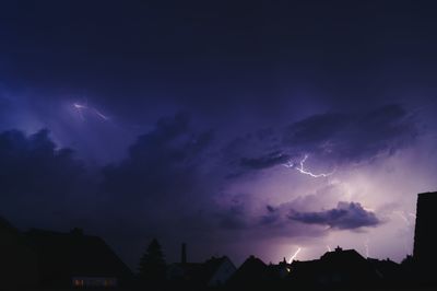 Silhouette of city against cloudy sky at night