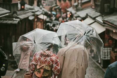 Rear view of people walking on wet street during rainy season