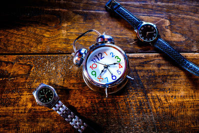 Close-up of alarm clock and wristwatches on table