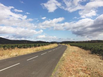 Road amidst field against sky