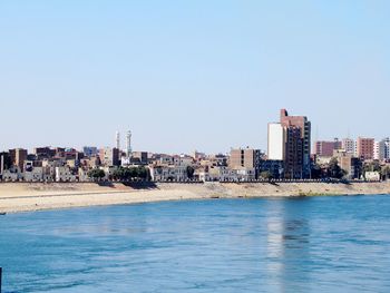 Scenic view of sea and buildings against clear sky