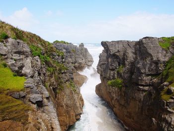 Scenic view of sea and cliff against sky