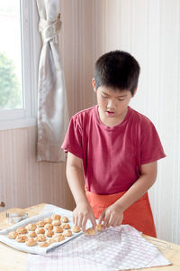 Boy placing food on cooling rack at table