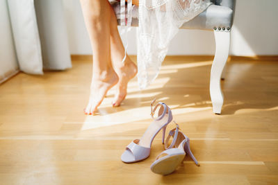 Low section of woman wearing shoes on hardwood floor