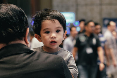 Rear view of man carrying son during event