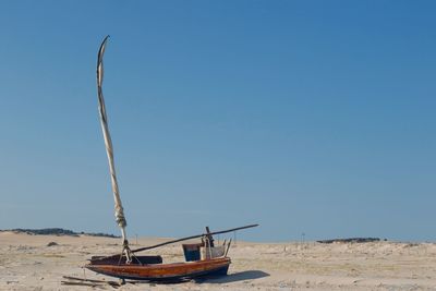 Ship moored on beach against clear blue sky