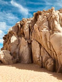 Rock formation on beach against sky