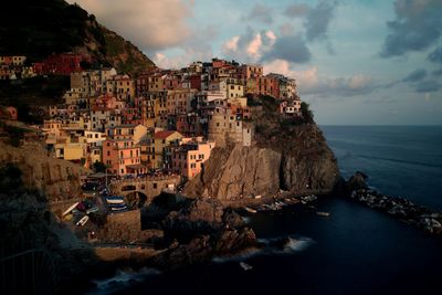 Houses on cliff at manarola in sea during sunset