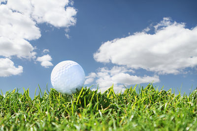 Close-up of golf ball on field against sky