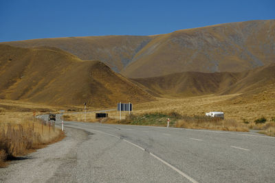 Road by mountains against sky