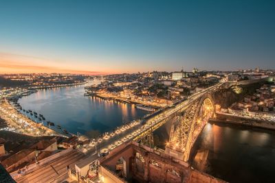 High angle view of illuminated city by river against sky