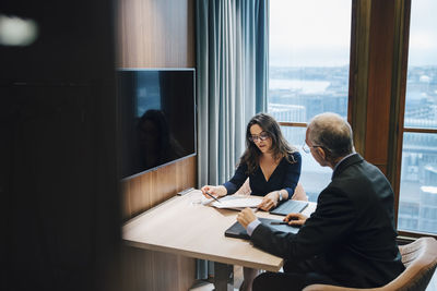 Businesswoman discussing with male entrepreneur over document in board room at office