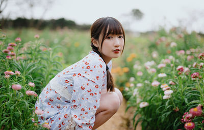 Portrait of young woman standing amidst plants