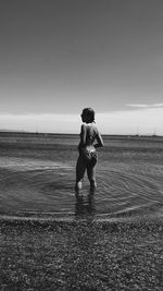 Full length of teenage girl standing on beach against clear sky