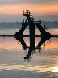 Silhouette pier on lake against sky during sunset