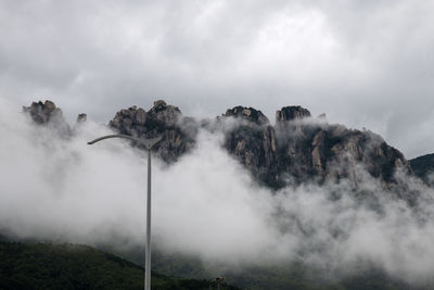 Scenic view of fogged mountain against sky