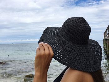 Close-up of woman wearing sun hat while standing at beach against sky