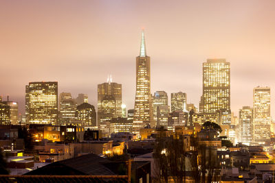 Illuminated buildings in city against sky