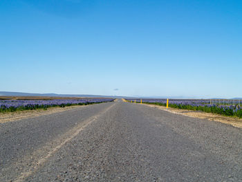 Surface level of road against clear blue sky