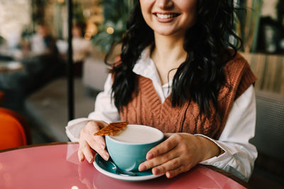 Midsection of woman holding coffee cup at cafe