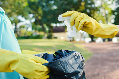 Cropped hands wearing gloves holding garbage bag at park