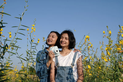 Portrait of happy friends against plants against sky