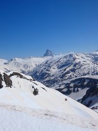 Scenic view of snowcapped mountains against clear blue sky