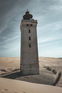 Lighthouse on beach against sky