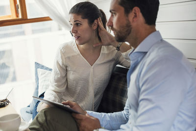 Businessman and businesswoman with digital tablet looking away in office