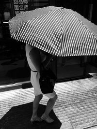 Full length rear view of woman standing on rainy day