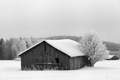 House on snow covered landscape against clear sky