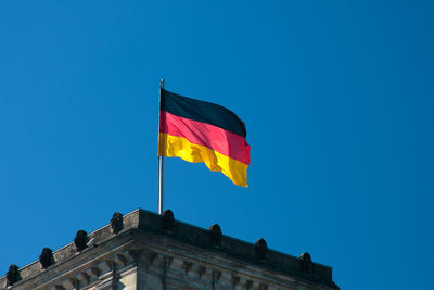 Low angle view of flag against blue sky