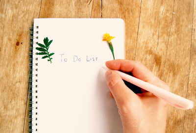 Close-up of hand writing on note pad on desk