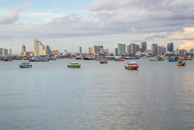 Boats in sea by buildings against sky