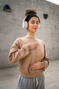 Portrait of young woman standing against wall
