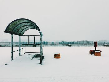 Gazebo by sea against clear sky during winter