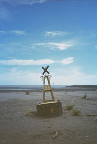 Traditional windmill on beach against sky