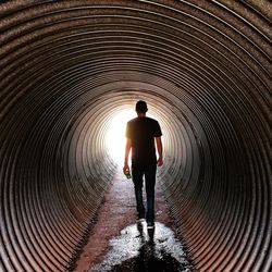 Rear view of silhouette man standing in tunnel