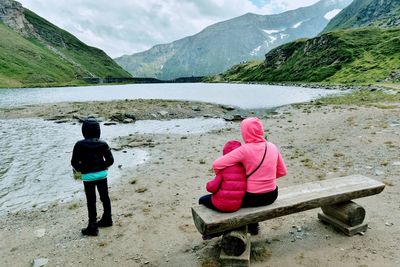 Rear view of women sitting by mountains against sky