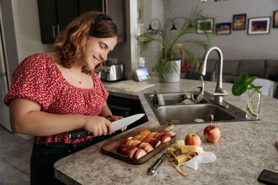 Portrait of young adult women making pastry with apples cutting apples and smiling