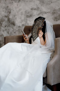 Midsection of woman reading book while sitting on bed