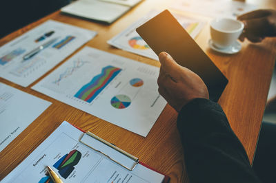 Cropped hand of businessman using digital tablet at desk in office