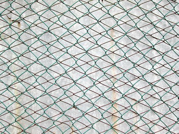 Full frame shot of chainlink fence against gray wall