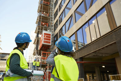 Female engineers in reflective clothing discussing at construction site