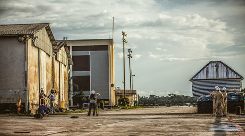 Construction workers working on road by houses against sky